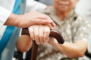 Adult child holding an elderly parent’s hand in a nursing home after a serious fall